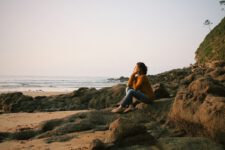 woman sitting near sea during daytime