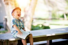 boy sitting on bench while holding a book